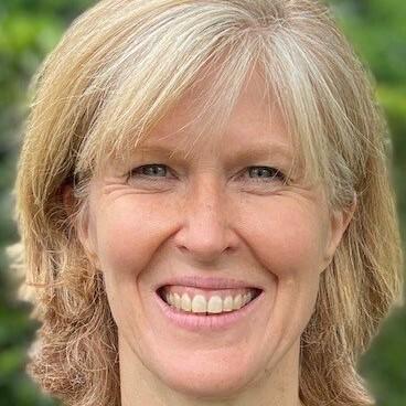 Porträt einer lächelnden Frau mit mittellangen, blonden Haaren vor einer grünem Hintergrund.