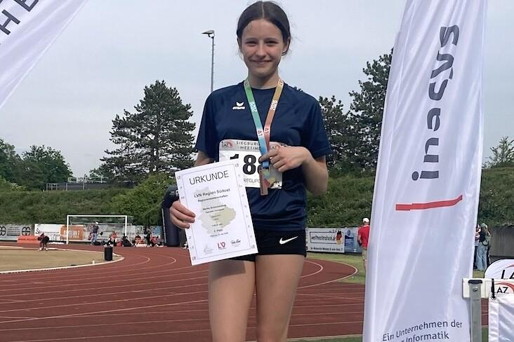 M&auml;dchen auf dem dritten Platz eines Siegertreppchens h&auml;lt eine Urkunde und Medaille bei einer Sportveranstaltung.