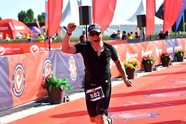 Ein jubelnder Triathlet mit Startnummer 582 l&auml;uft auf einer roten Laufstrecke w&auml;hrend eines Wettbewerbs.