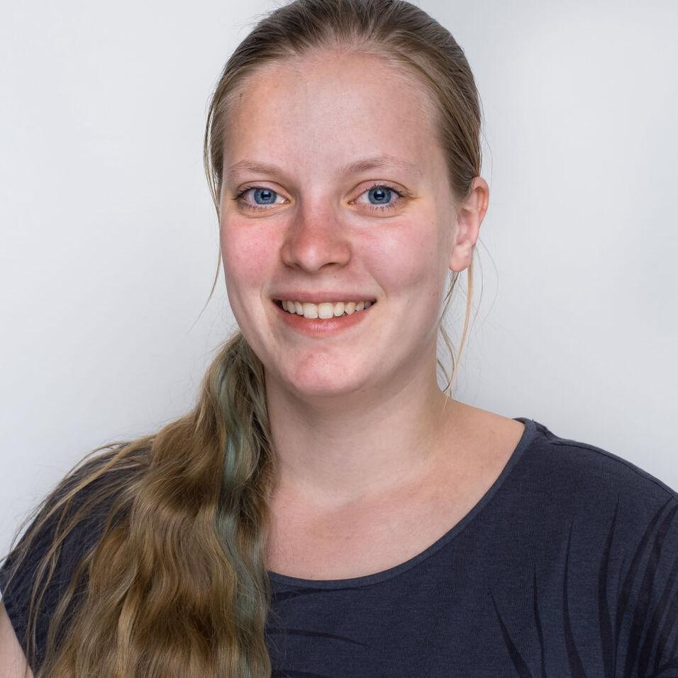 L&auml;chelnde Frau mit langen, blonden Haaren und blauen Augen vor einem hellen Hintergrund.