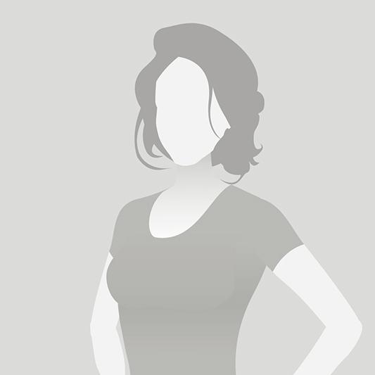 Profil einer Frau mit lockigem Haar, die in einem T-Shirt steht und den Oberkörper leicht zur Seite neigt.