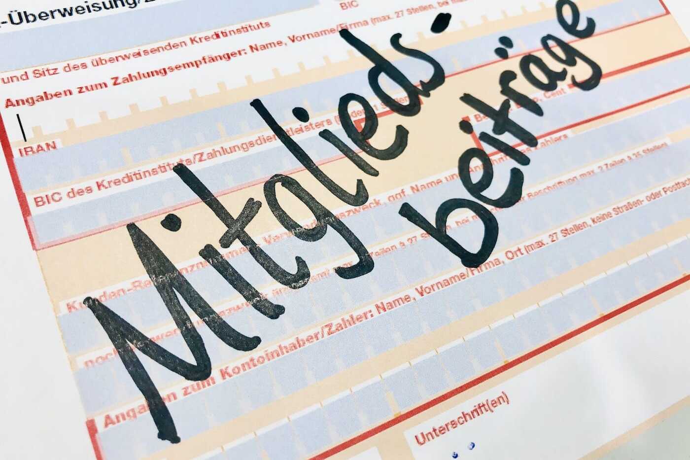 Zahlungs&uuml;berweisung mit dem handgeschriebenen Wort "Mitgliedsbeitr&auml;ge" auf einem Formular.