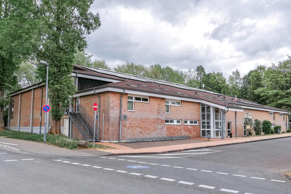 Fassade eines modernen, einst&ouml;ckigen Geb&auml;udes aus Ziegelstein, umgeben von B&auml;umen und einem ruhigen Stra&szlig;enbereich.